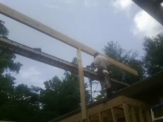 Carpenter setting a ridge beam over a new addition frame — Ice Dam Removal by Roofing Brothers in Arden